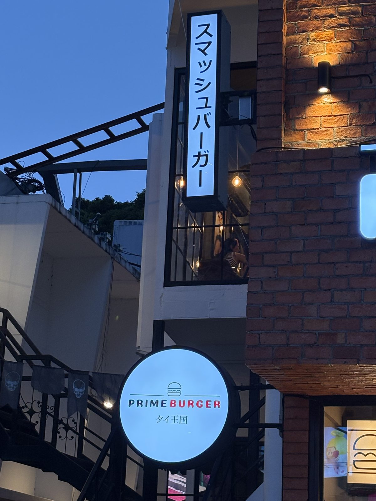 PRIME BURGER の「スマッシュバーガー」の縦の看板と「タイ王国」と書かれた丸い看板