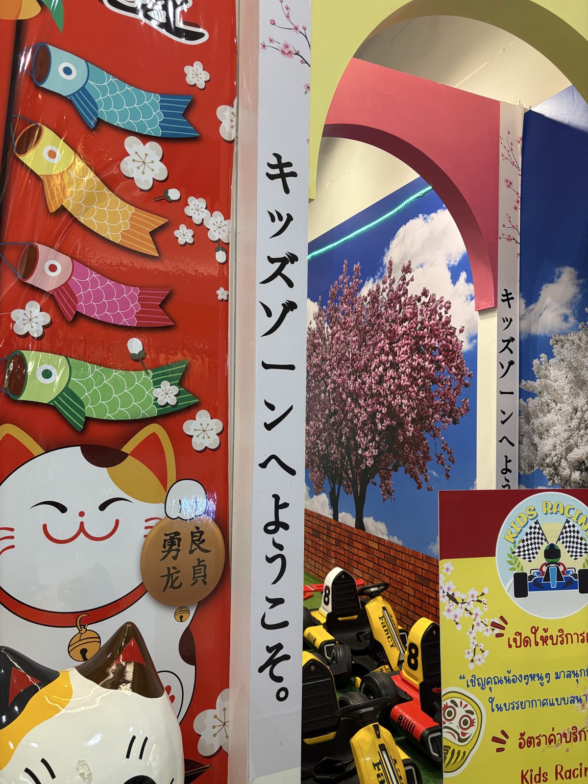 こいのぼりと招き猫と桜が描かれた「キッズゾーンへようこそ。」の看板